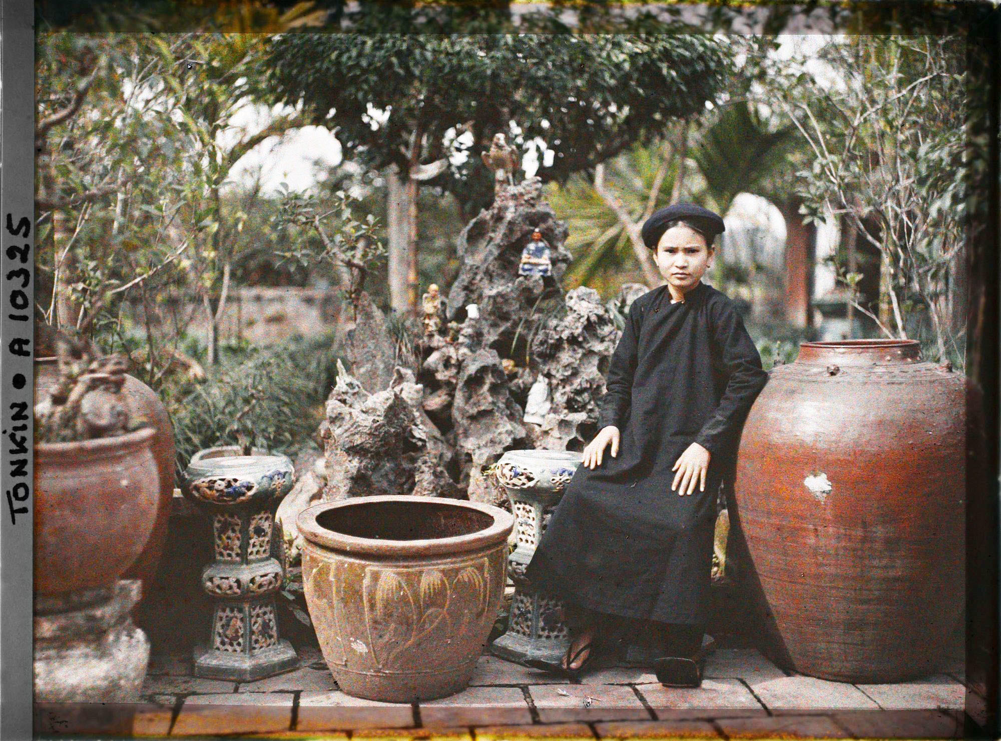 Tiểu thư con một gia đình giàu có ở miền Bắc Việt Nam ngồi trong vườn cảnh nhà mình.